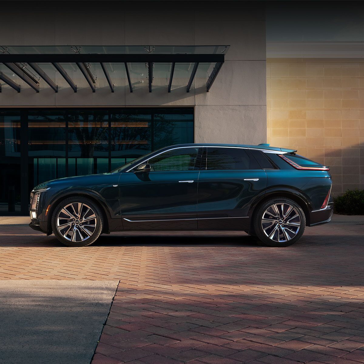 A side view of a Cadillac LYRIQ parked outside of a building entrance