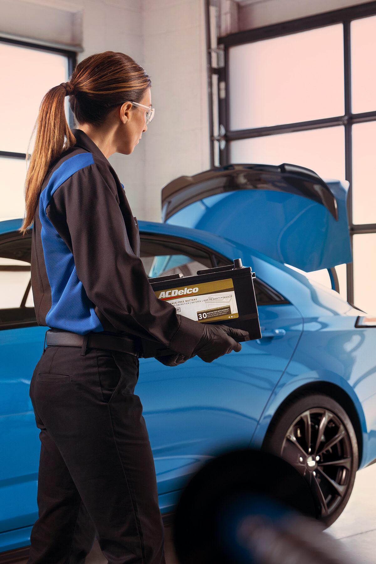 Cadillac Certified Service Technician Carrying an ACDelco Gold Battery to Install in a Vehicle