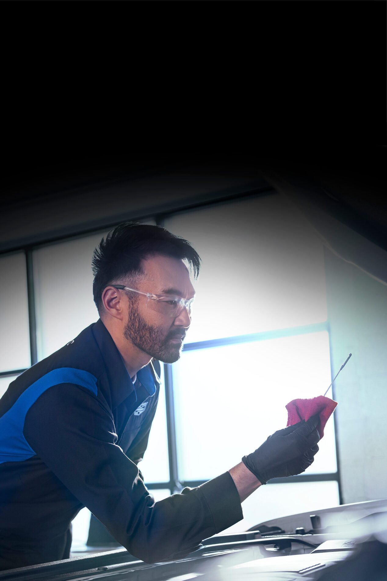 Cadillac Certified Service Technician Checking the Vehicle's Oil Level on a Dipstick