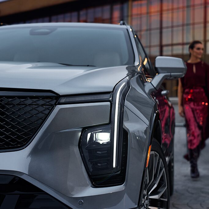 Front View of a Silver Vehicle with a Woman Walking by in the Back