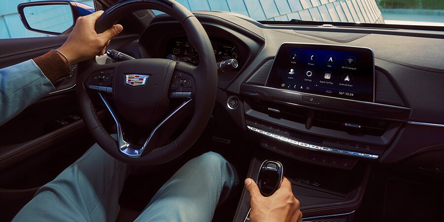 A Person in the Driver Seat Holding on to the Steering Wheel and Gear Shift inside a Cadillac