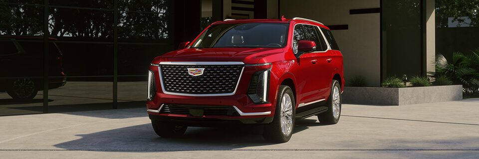 Three Quarters View of a Red Cadillac Vehicle Parked in Front of a Building under a Sunny Day