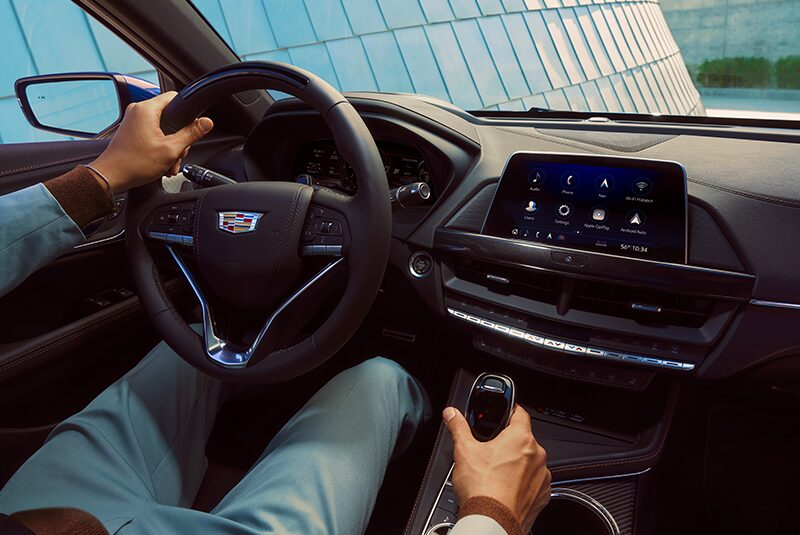 A Person in the Driver Seat Holding on to the Steering Wheel and Gear Shift inside a Cadillac