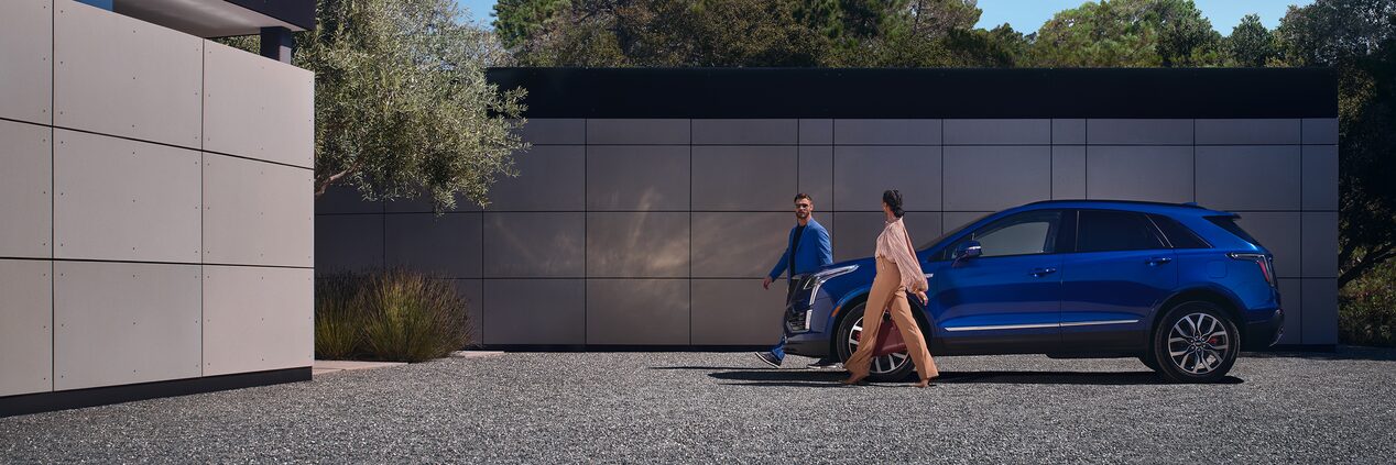 A Couple Walks Away from Their Parked XT5 As They Approach Their Luxurious Home