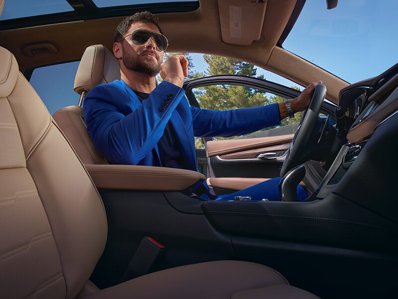 A Man Wearing Stylish Shades &  a Blue Suit Sits Comfortably in the Passenger Seat of a Cadillac XT5