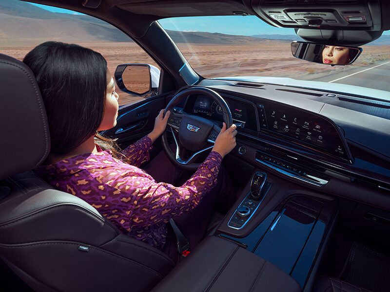 A Woman Holds the Steering Wheel of Her Cadillac SUV with Both Hands As She Enjoys Her Smooth Ride
