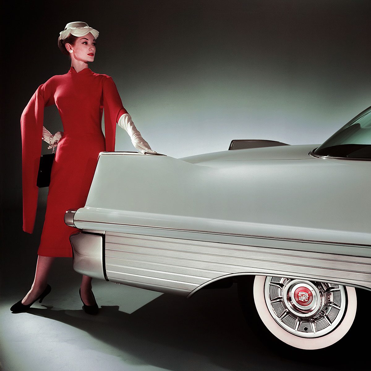 Woman In A Red Dress Posing Next To Rear End Of Classic Cadillac