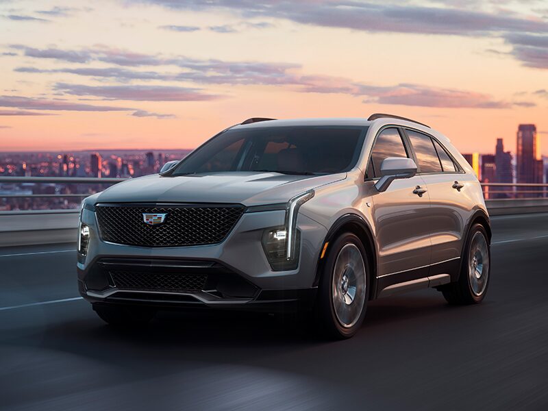 The 2025 Cadillac XT4 Driving on an Overpass with the City in the Distance During a Sunset