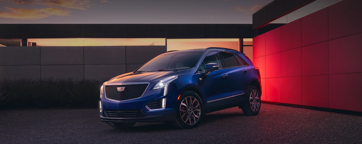 The Beautiful 2025 Cadillac XT5 Parked at Dusk in Front of Modern House With Lights On