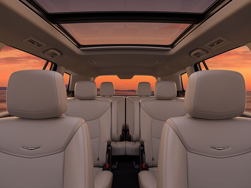 Three Rows of Tan Leather Seats Inside the New Cadillac XT6 Parked Under the Sunset