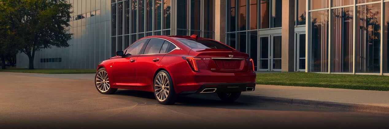 Rear View of the 2024 Cadillac CT5 in Radiant Red Tintcoat Parked Near an Industrial Building