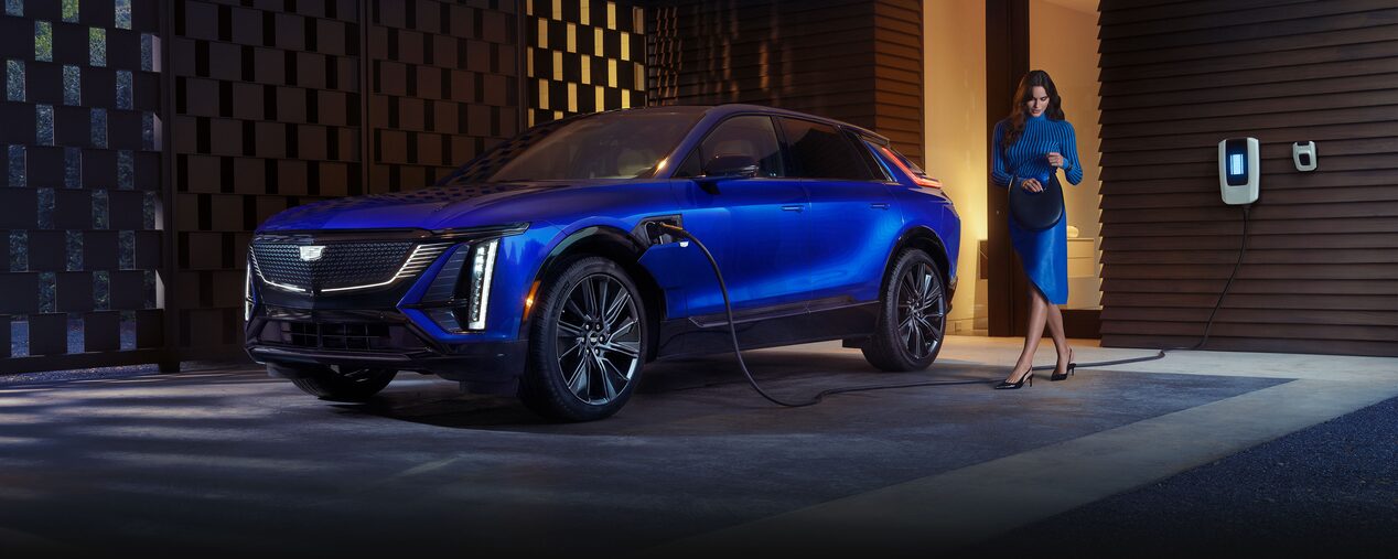 A Woman Looking in Her Purse Next to a Charging Blue 2025 Cadillac LYRIQ