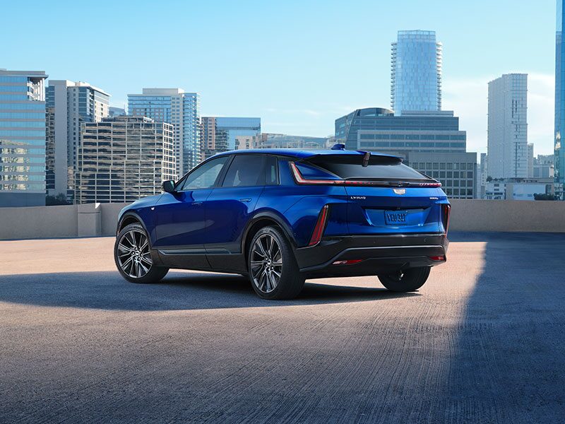 Three-Quarter Rear View of a Blue 2025 Cadillac LYRIQ Parked Overlooking the City Skyscrapers