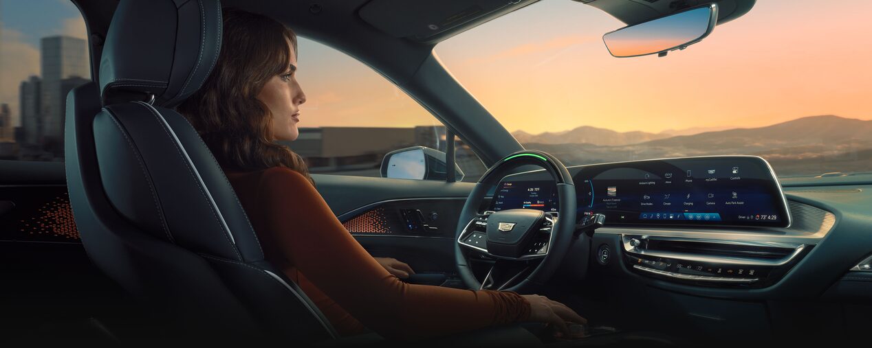 Passenger View of a Woman in Driver's Seat of the 2025 Cadillac LYRIQ During a Sunset