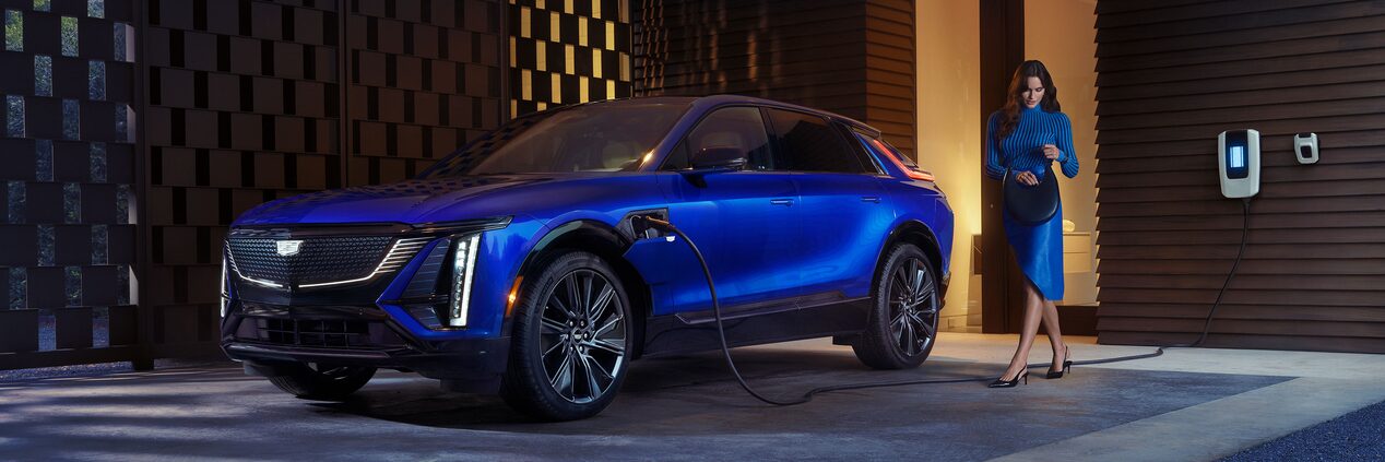 A Woman Looking in Her Purse Next to a Charging Blue 2025 Cadillac LYRIQ