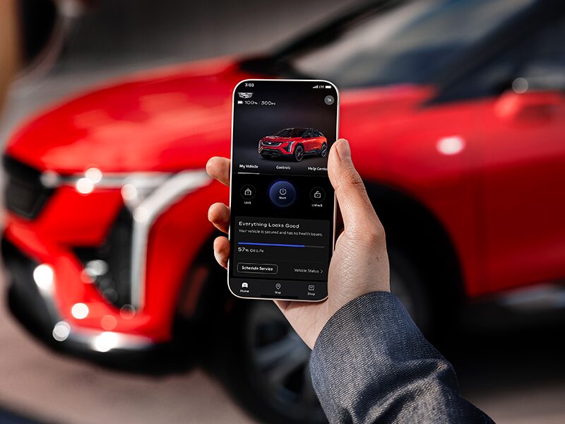 A Man Holding a Phone and Looking at the 2025 OPTIQ Range in the myCadillac Mobile App