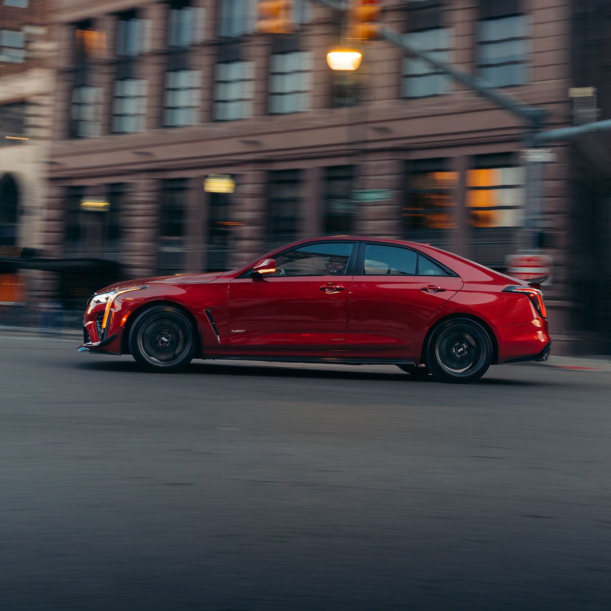 The Side Profile of a Red 2025 CT4-V Speeding Past Downtown