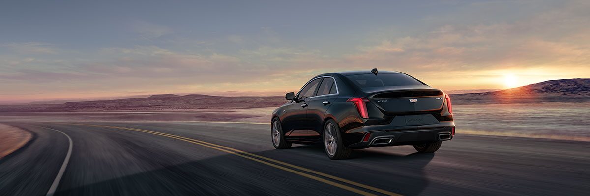 Three Quarters Rear View of a Black 2026 CT4 Driving Down a Desert Road