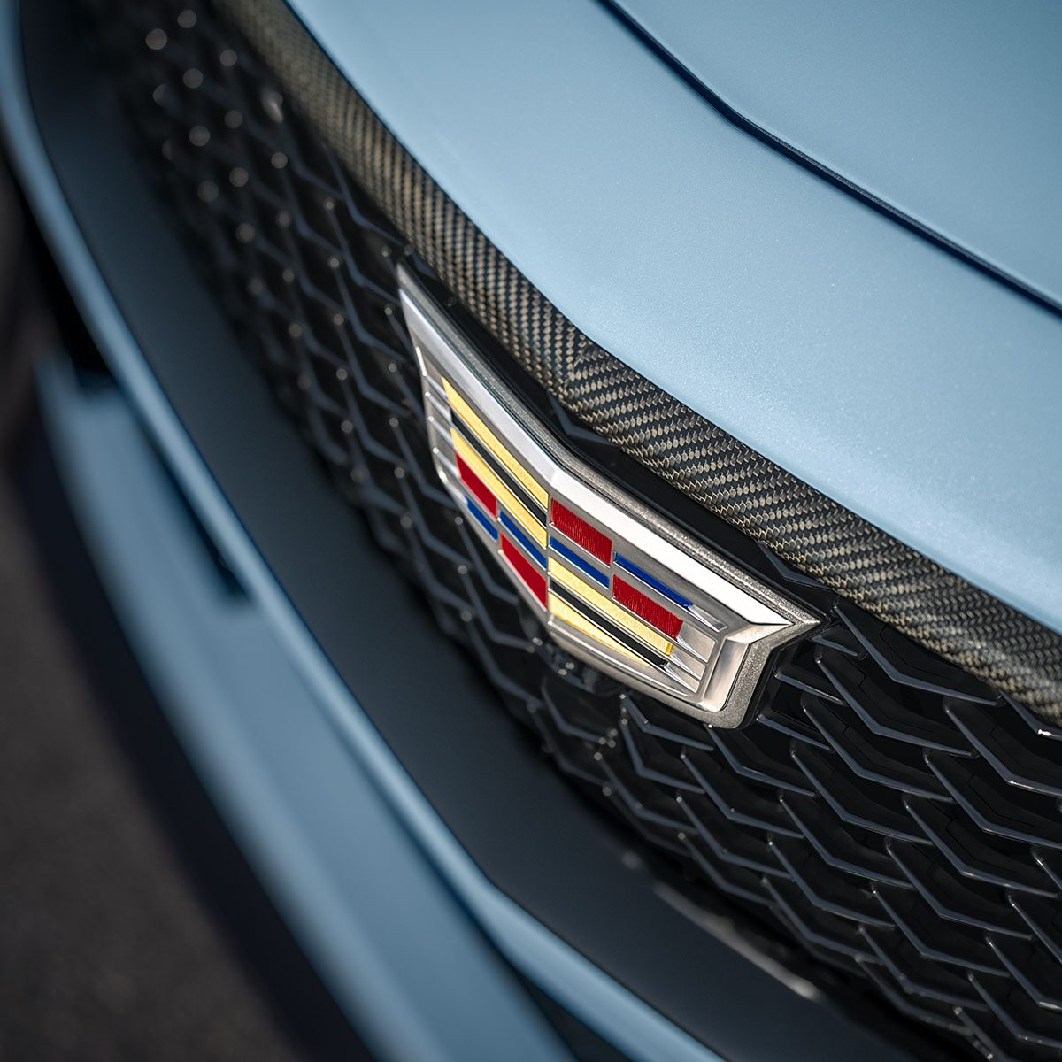 Close-up of a Cadillac Emblem on the Grille of a Light Blue 2025 CT5-V