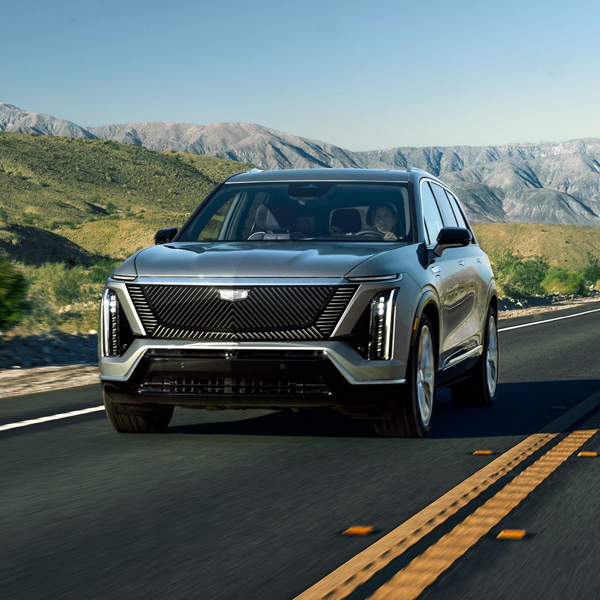 Three-quarter View of a 2026 VISTIQ Driving Down a Road Through the Grassy Mountains
