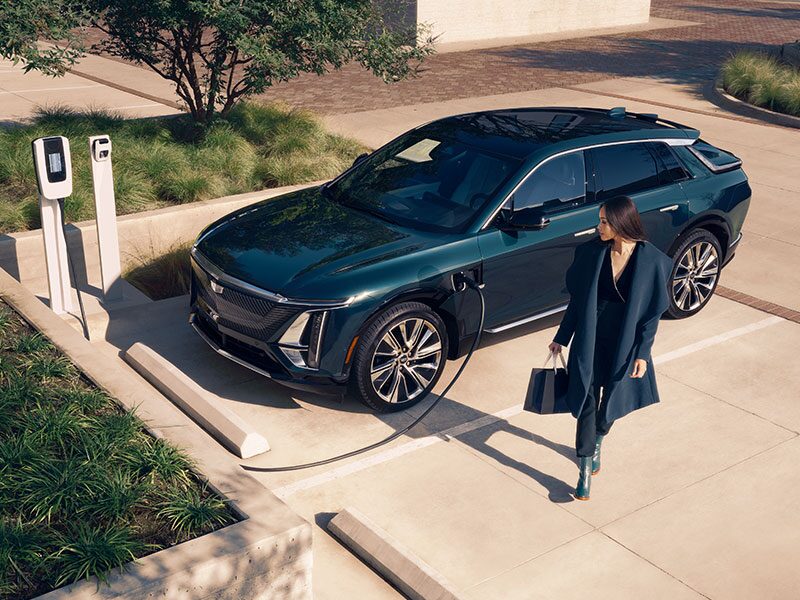 A Business Woman Walking Away From a Cadillac LYRIQ Charging at a Public Charger
