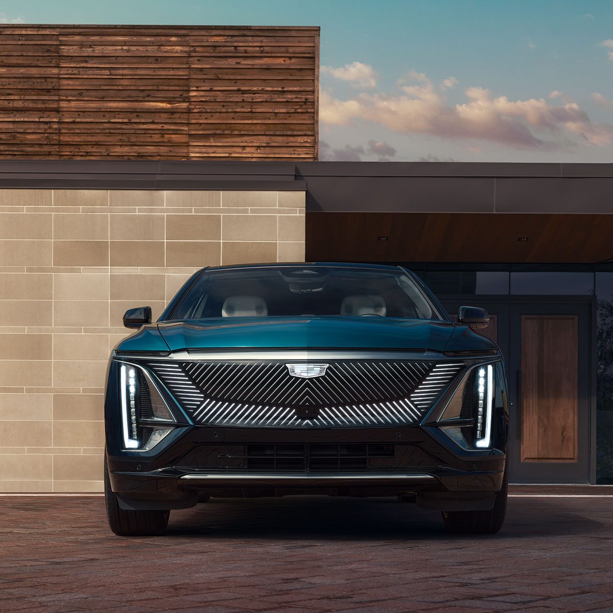 Front View of a Cadillac LYRIQ Electric SUV Parked Outside of a Luxurious Home