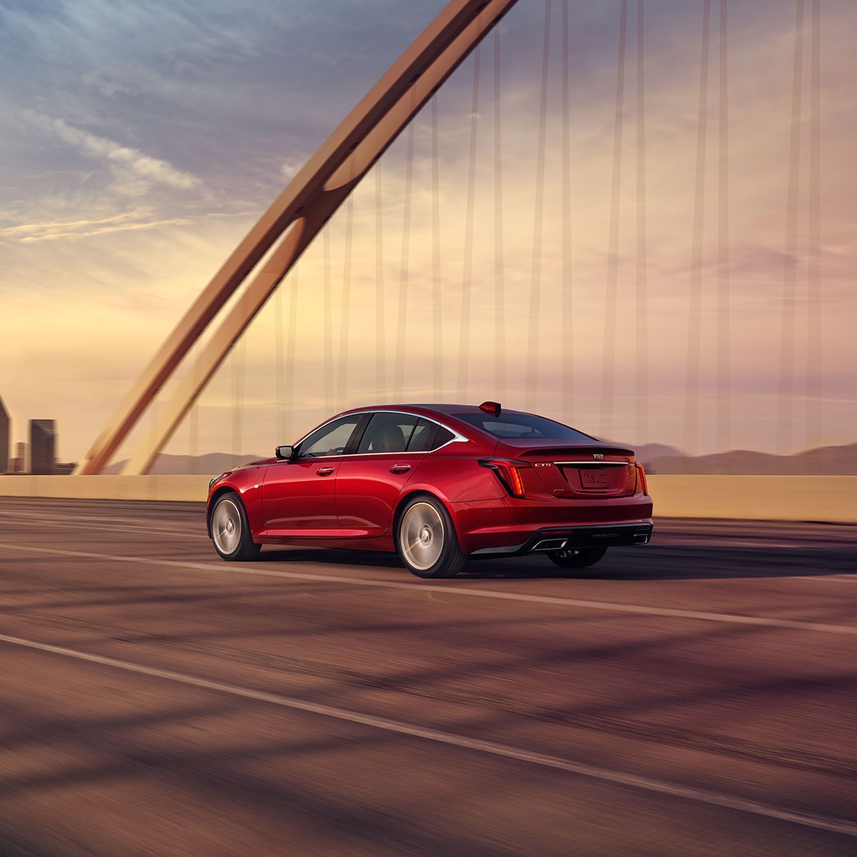 Side View of a Radiant Red Tintcoat 2026 Cadillac CT5 Driving on Bridge