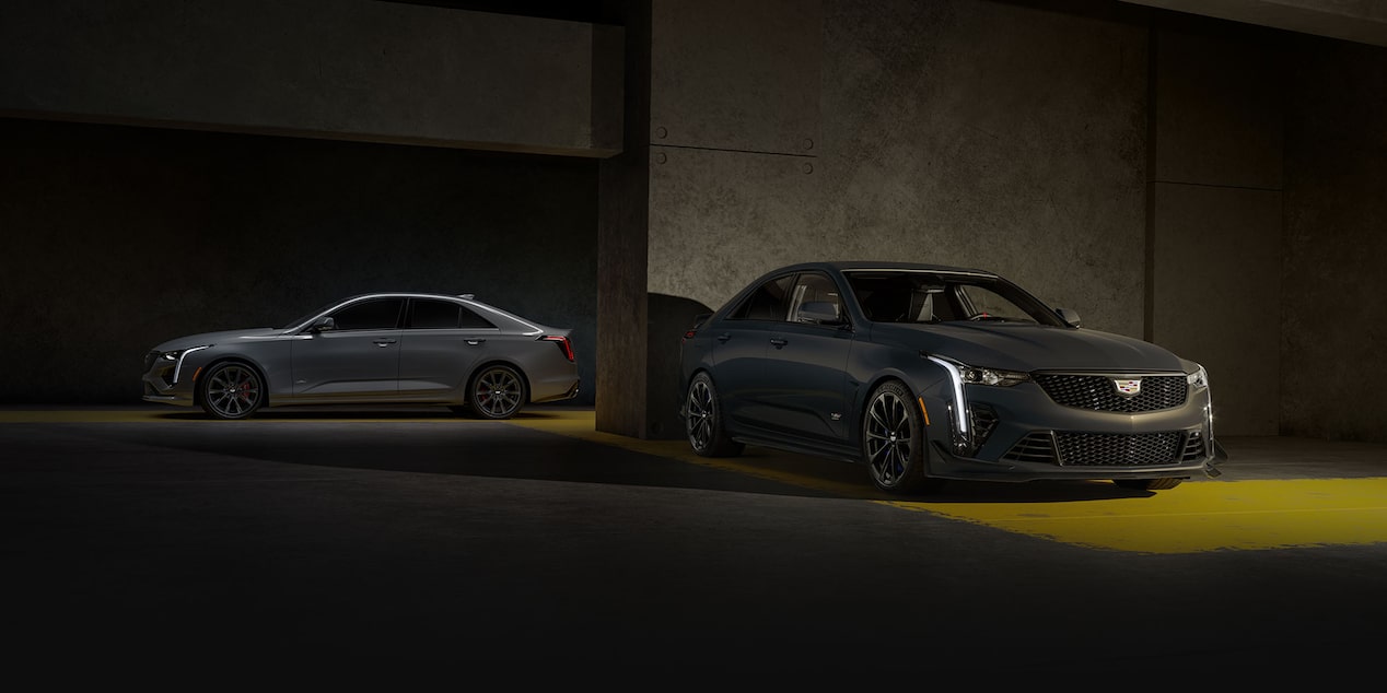 A Dark Gray Cadillac CT4-V Blackwing Sedan in the Foreground with a Lighter Gray Cadillac CT5-V Blackwing Sedan in the Background, Both in a Garage