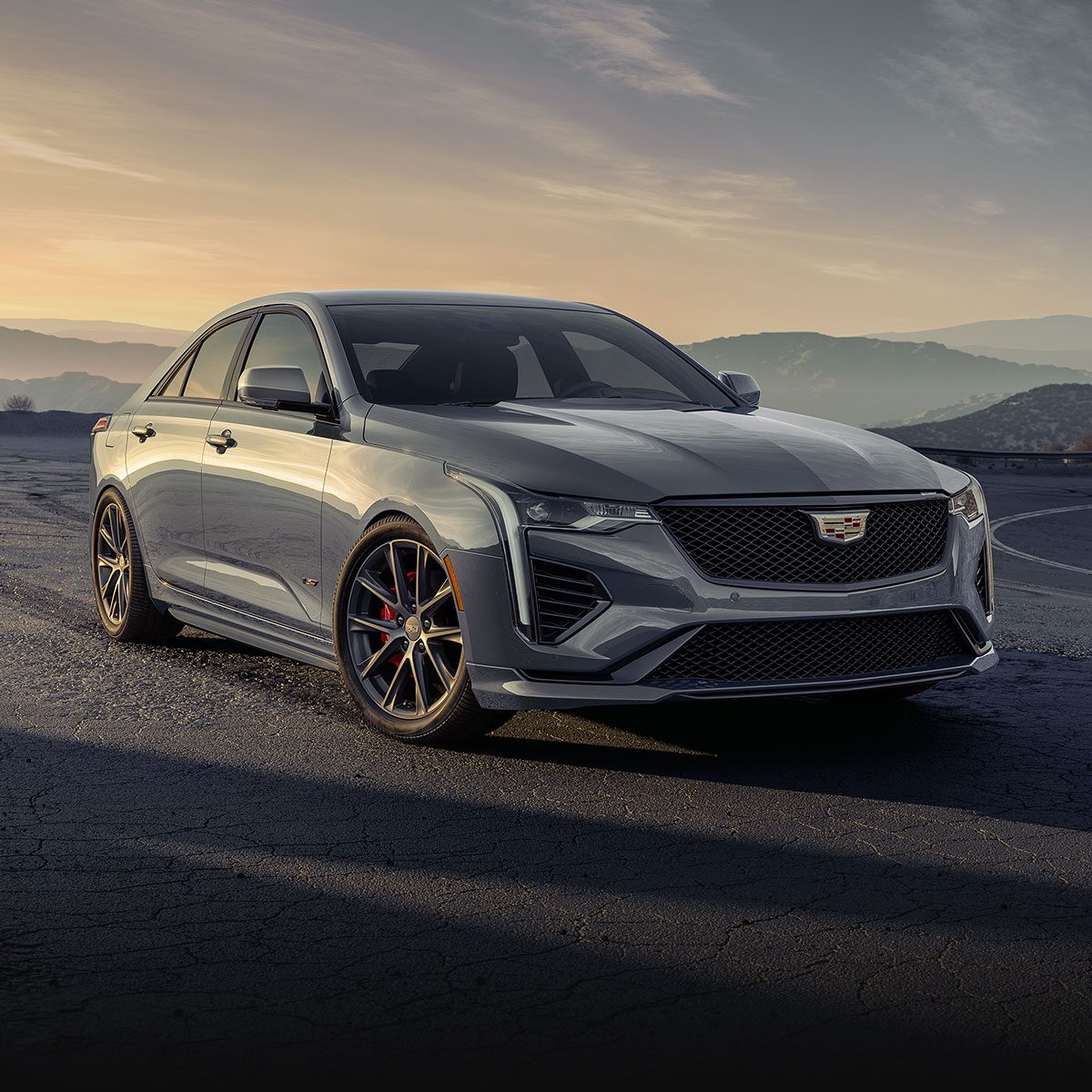 A Cadillac CT4-V Driving Down a Road with Hills in the Background.