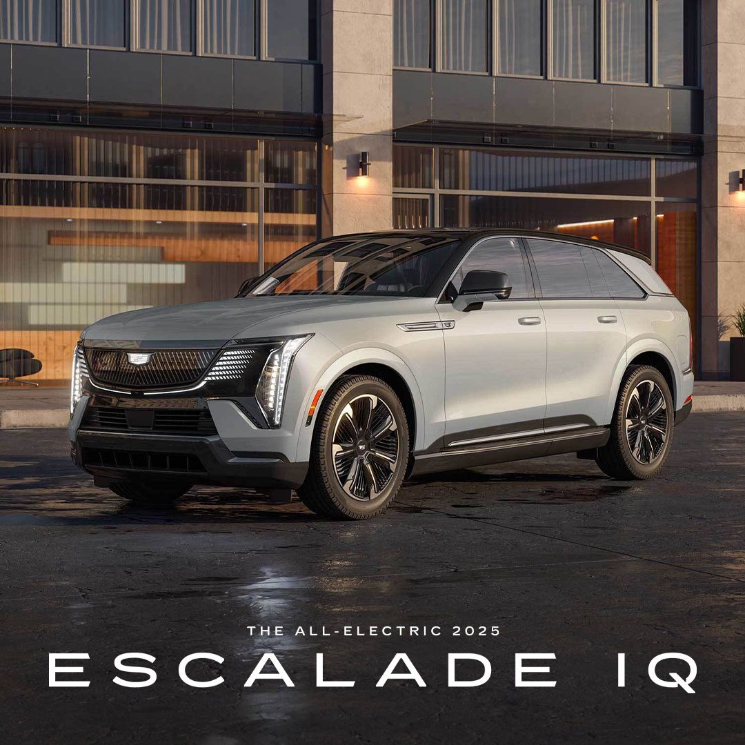 Three-quarter View of the 2025 ESCALADE IQ Parked by an Industrial Building
