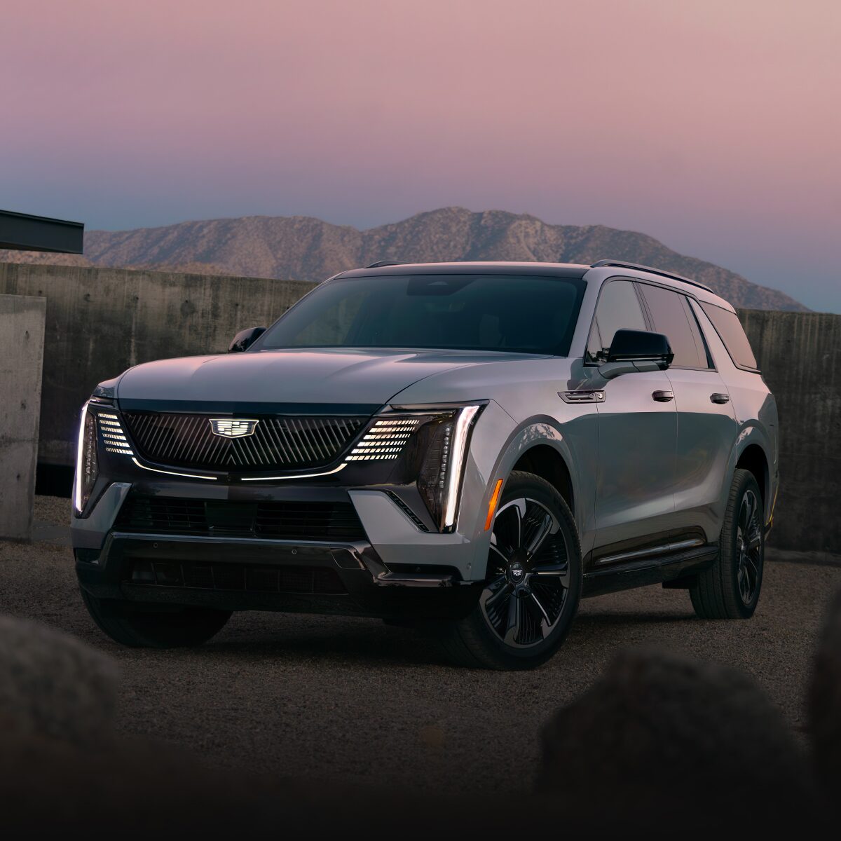 Front Three-Quarter View of the 2026 ESCALADE IQL Parked near a Concrete Wall During Dusk